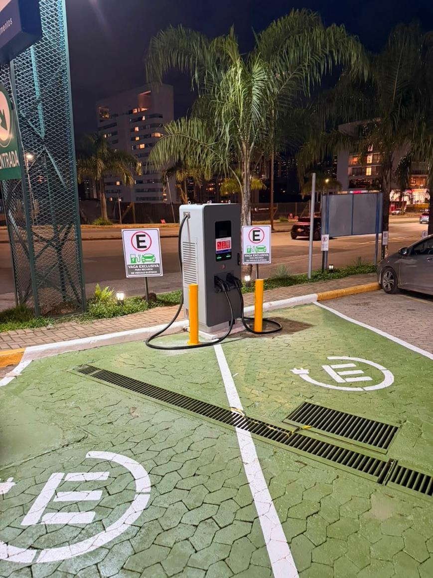 Carregador WePlug iluminado entre duas vagas exclusivas para veículos elétricos, à noite